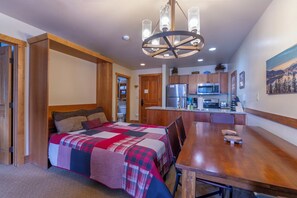A bedroom with a large bed, a wooden dining table, and a kitchen area with modern appliances. - 1BR+Murphy Bed/2 Bath in River Run Village close to the Keystone gondola (Keystone)