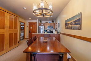A spacious dining area with a wooden table and chairs, a modern kitchen with stainless steel appliances, and a large wooden door. - 1BR+Murphy Bed/2 Bath in River Run Village close to the Keystone gondola (Keystone)