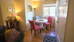 A cozy living room with a sofa, a dining table with chairs, a lamp, and a window with blinds. - Napa Valley Retreat in Calistoga! (Calistoga)