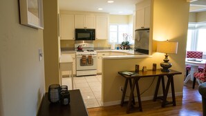 A kitchen with white cabinets, a microwave, an oven, and a dining area with a table and chairs. - Napa Valley Retreat in Calistoga! (Calistoga)
