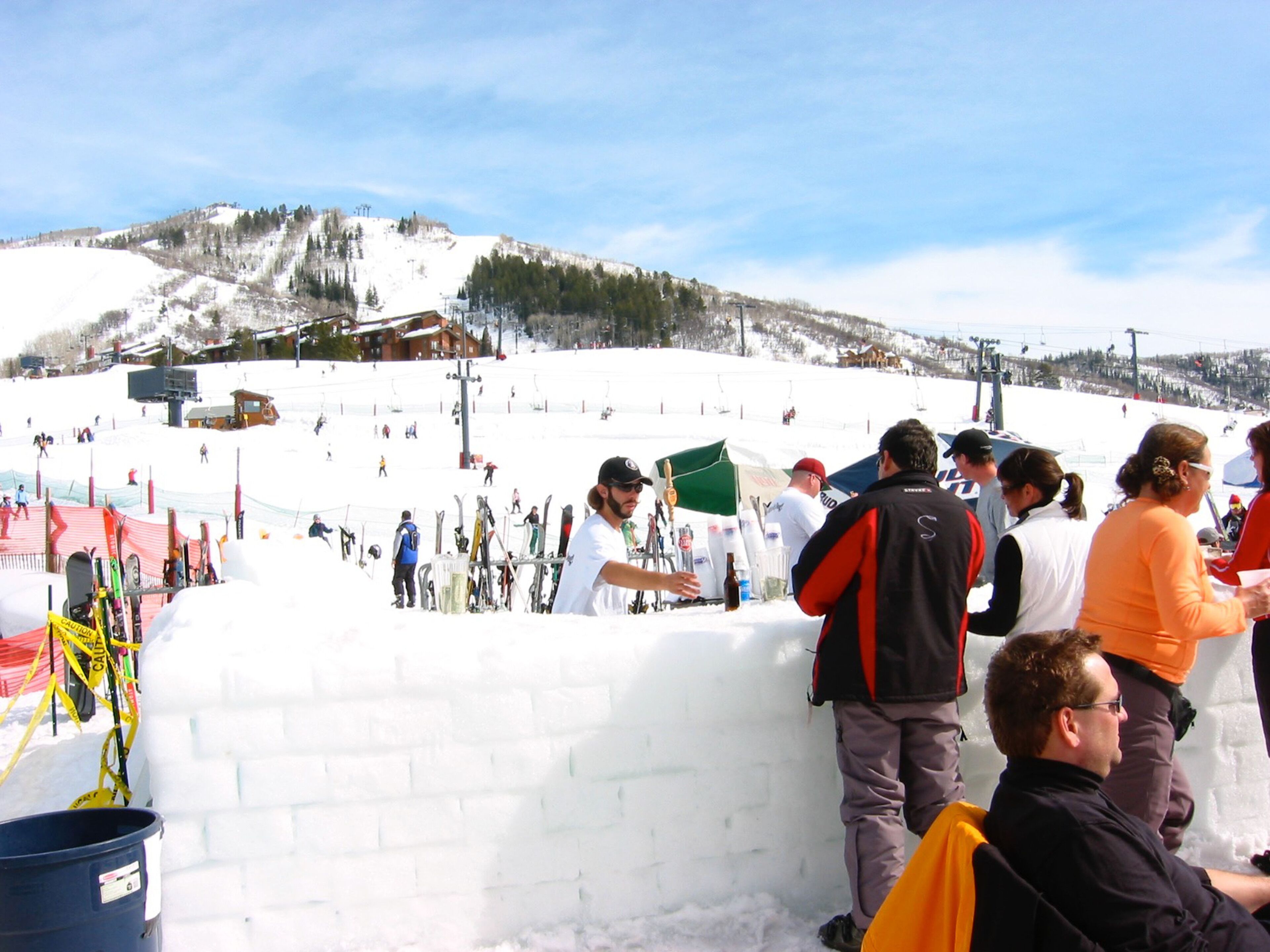 A snowy ski slope with people standing and skiing.