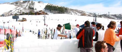 A snowy ski slope with people standing and skiing.
