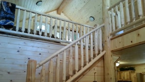 A wooden staircase with a white handrail, leading to a loft area with a window and a hanging tag. - 14 miles to Yellowstone entrance. Private HOT TUB.    (Island Park)
