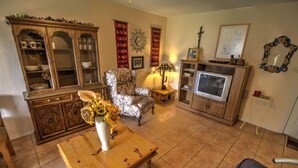 A living room with a wooden coffee table, floral vase, armchair, TV stand, and a cabinet. - Pet-Friendly Island Retreat | No Weight/Breed Limits | 1mi Clayton’s Beach Bar (South Padre Island)