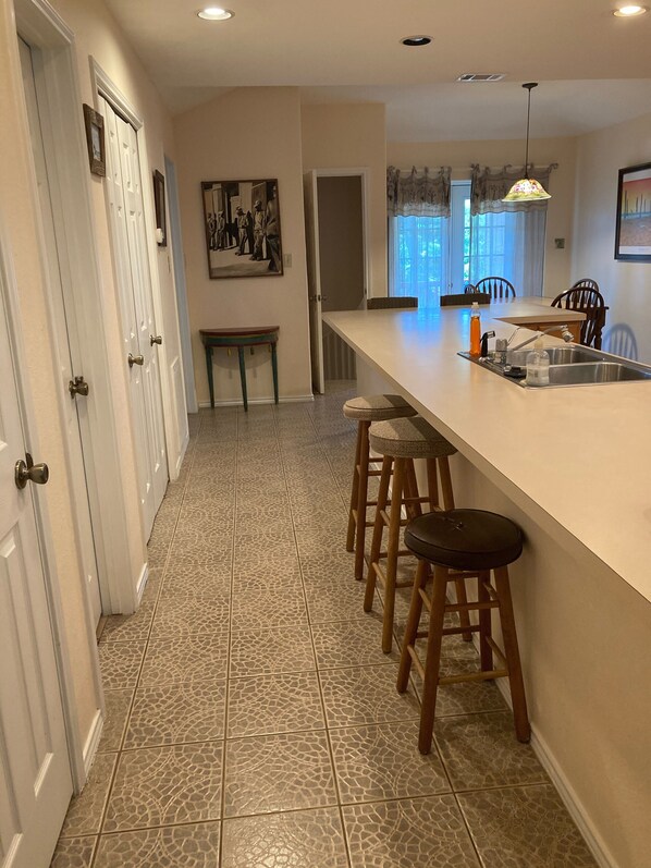 A kitchen with a white countertop, a sink, and a bar stool.