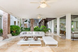 Relax in a spacious, airy space with a high ceiling and glass wall offering a view of the outdoors.