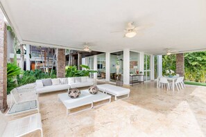 Relax in this open-plan living area with a high ceiling, ceiling fans, and comfortable seating for four.