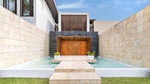 Edifici modern amb una porta de fusta, una piscina i una petita zona de jardí.