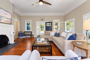 A living room with a fireplace, a sofa, a coffee table, and a ceiling fan.