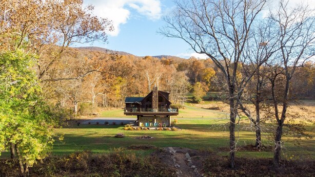 A cabin with a deck and a view of a river and forest. - Chalet In West Virginia on the Cacapon River. Sleeps 8 (Great Cacapon)
