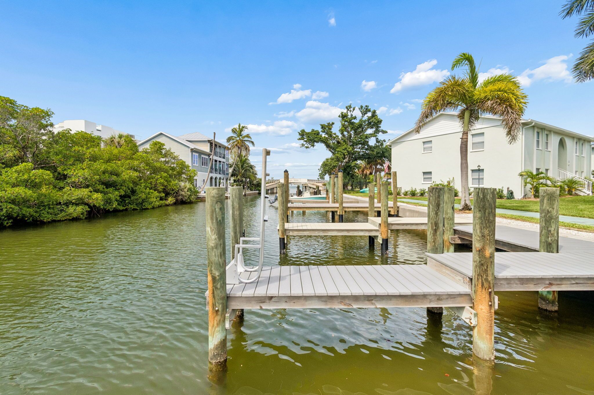A waterfront property with a dock, a bridge, and a building with a white facade.
