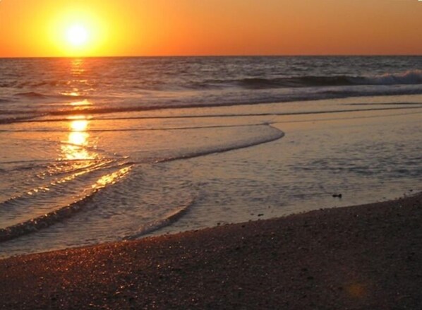 A beach at sunset with waves gently lapping onto the shore.