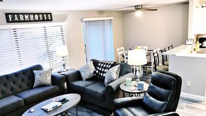 A modern living room with a sofa, armchair, coffee table, and a dining area with a table and chairs. - Lake Front unit ready 4 you!  - sleeps 12 in beds, w/king bed, WiFi, pets (Crossville)