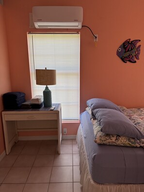 Cozy retreat with a single bed, nightstand, and window with blinds.