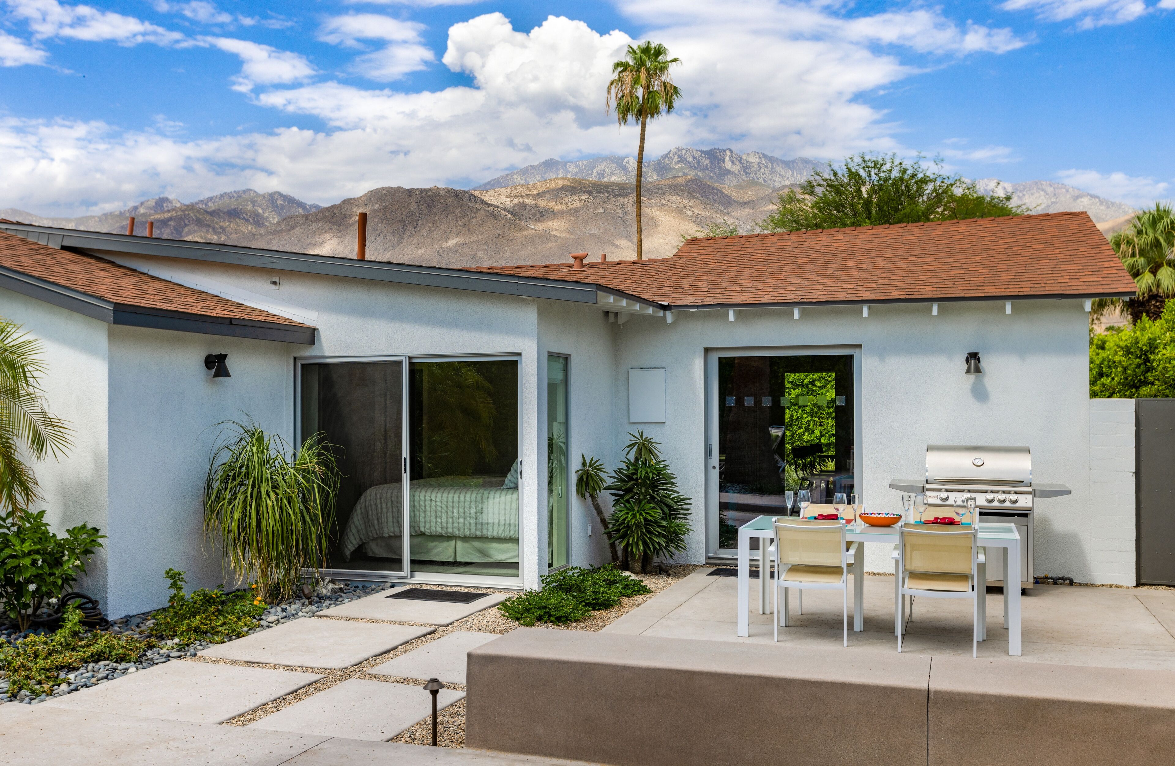 A modern house with a patio, a sliding glass door, and a barbecue area.