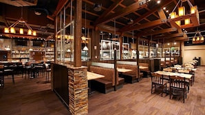 A restaurant with wooden beams, stone pillars, and multiple seating areas including booths and tables. - One Bedroom Master ski in-out @ Grand Lodge on Peak7 (Breckenridge)