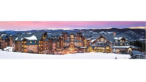 A large lodge with multiple floors and a central entrance, surrounded by snow-covered mountains. - One Bedroom Master ski in-out @ Grand Lodge on Peak7 (Breckenridge)