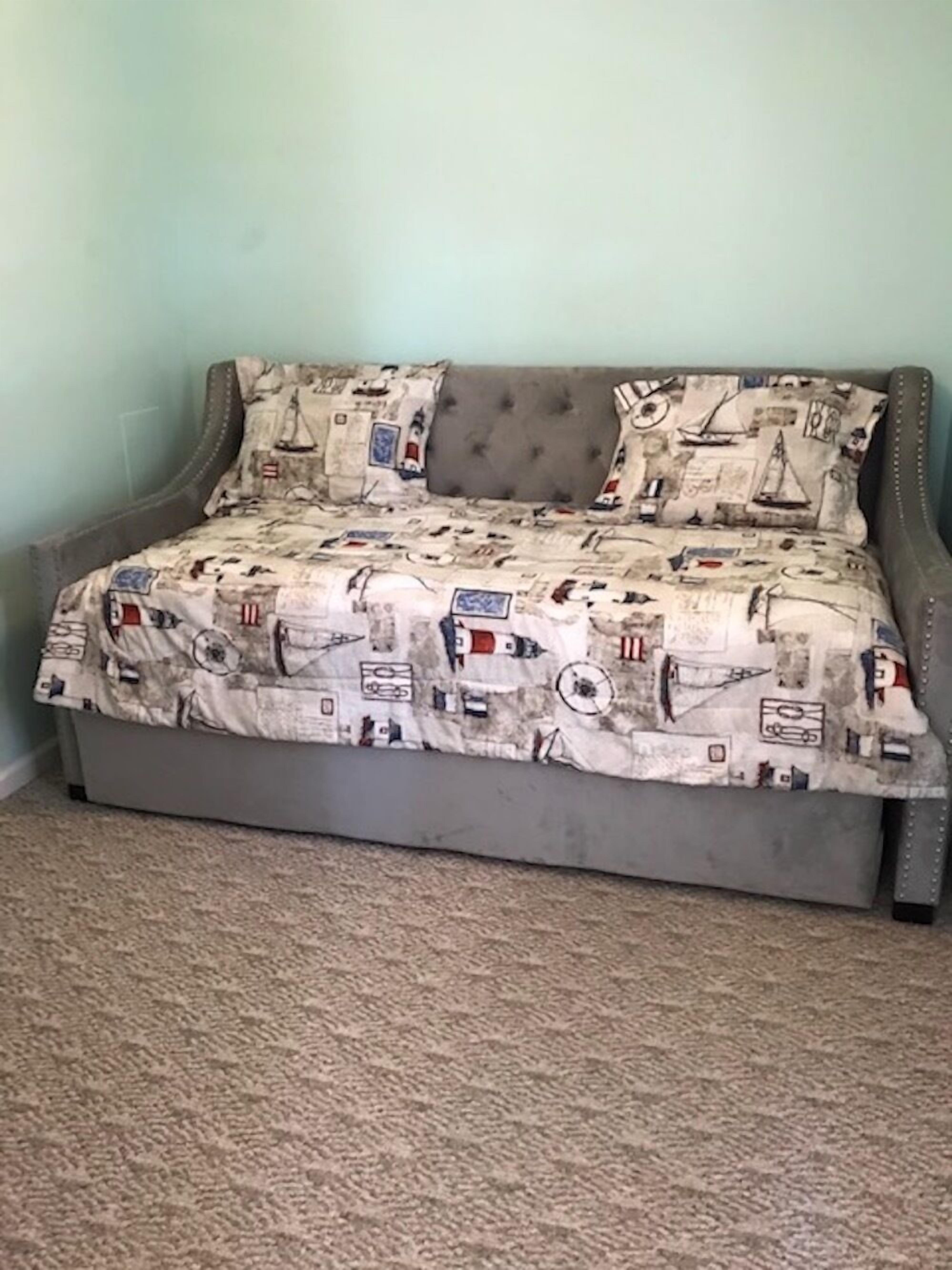 Een bed met een bedovertrek met patroon en twee kussens, voor een lichtblauwe muur.
