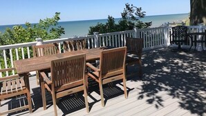 Une terrasse en bois avec une table et des chaises, donnant sur une étendue d’eau.