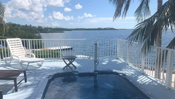 A deck with a hot tub, lounge chairs, and a view of the water. - Tropical Paradise - Ocean front with swim spa (Cudjoe Key)