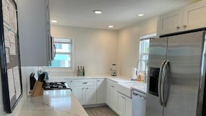 A modern kitchen with white cabinets, stainless steel appliances, and a wooden countertop. - Tropical Paradise - Ocean front with swim spa (Cudjoe Key)