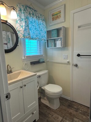 A bathroom with a toilet, sink, vanity, and a window with blinds. - Ocean View Family Home! Games, Hammocks & Chill Space Underneath. Walk to Shops! (Ocean Isle Beach)