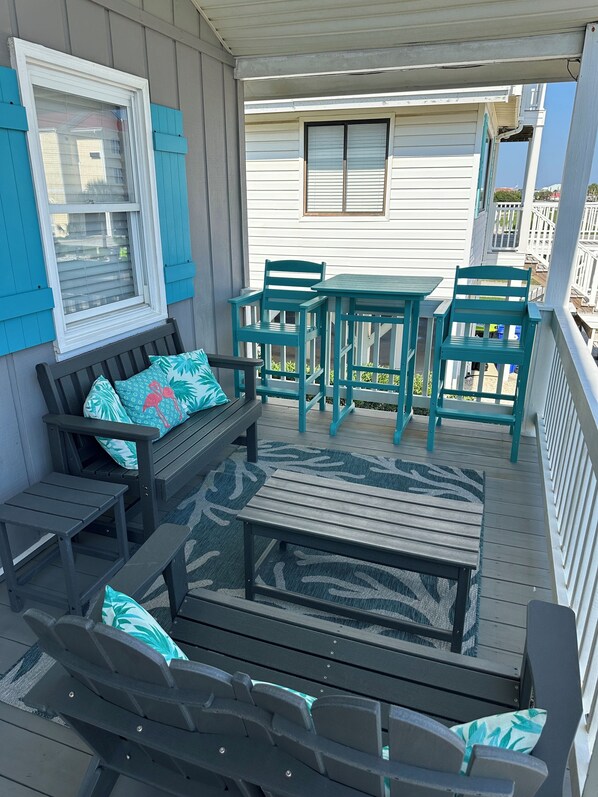 Eine überdachte Terrasse im Freien mit einer Holzbank, einem kleinen Tisch und passendem Stuhl.
