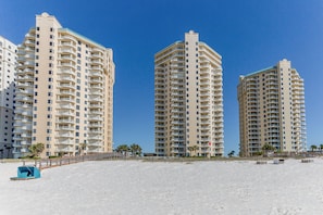 Three high-rise buildings with balconies, a sandy beach, and a wooden fence. - Stunning Ocean Views ~ Indoor / Outdoor Pools / Hot Tub ~ The Perfect Escape! (Pensacola)