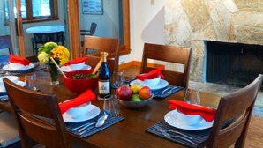 Een eettafel gedekt met rode servetten, borden en een schaal fruit.