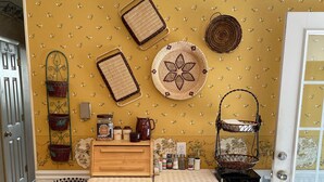 Een keuken met rieten meubels, een gele wand met een patroon en diverse keukengerei.