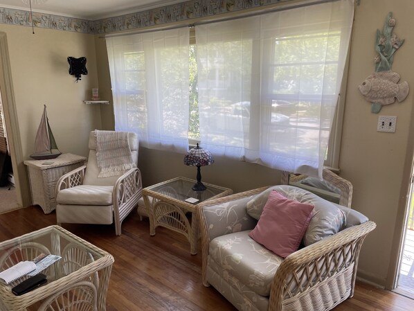 A cozy living room with wicker furniture, a glass coffee table, and a decorative lamp.