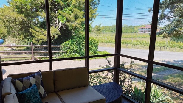 Una habitación con zona de estar acolchada, ventanas amplias y vistas a un viñedo.