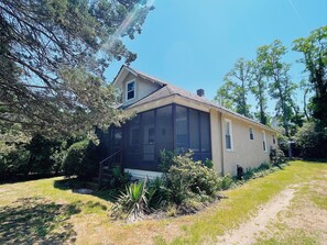 Situated in a wooded area, this single-story house offers a serene and environment with a large porch and well-maintained lawn.