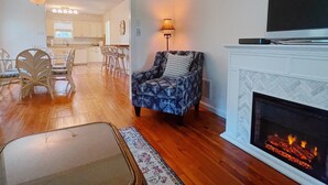 Una sala de estar con chimenea, televisor y comedor con sillas y una mesa.