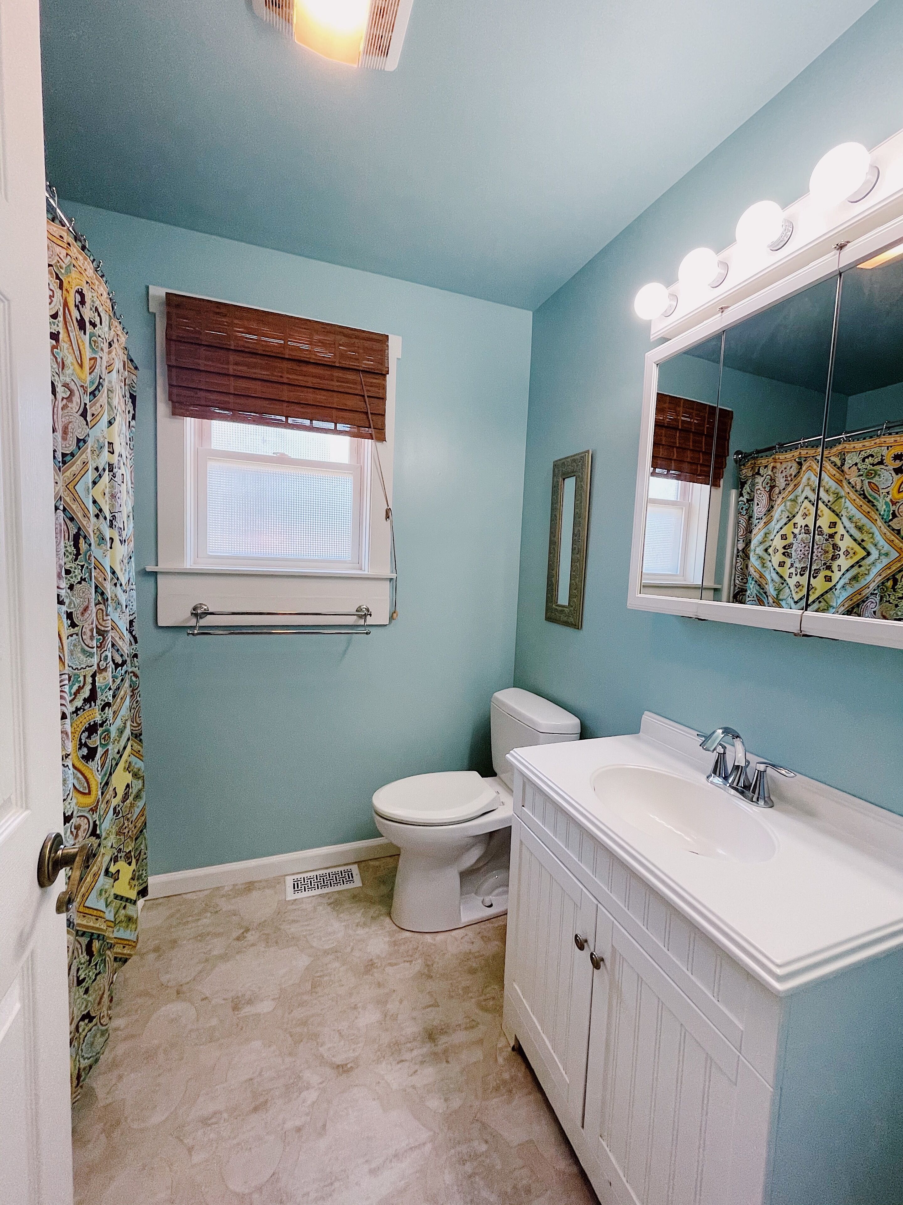 A bathroom with a toilet, sink, and mirror.