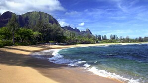 A beach with clear waters, a sandy shore, and a backdrop of green mountains. - Luxury Beachfront Home in Haena AC, Pool  TVNC5141 (Hanalei)