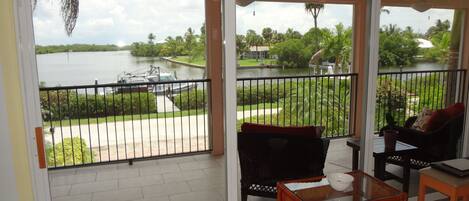 A balcony with a view of a lake, a boat, and greenery.