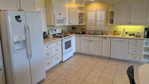 A kitchen with white cabinets, a refrigerator, a microwave, and a sink. - The Bokeelia Boathouse, waterfront, Boat Dock, Pine Island, Florida (Bokeelia)