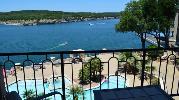 A balcony with a view of a swimming pool and a body of water with boats. - Amazing top floor view in a newly renovated Lake Travis Condo on Private Island (Lago Vista)