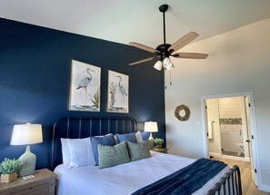 A bedroom with a bed, nightstands, a ceiling fan, and wall art. - Amazing top floor view in a newly renovated Lake Travis Condo on Private Island (Lago Vista)