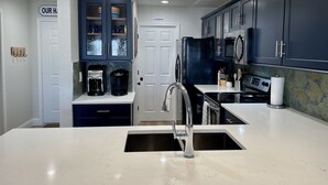 A modern kitchen with dark blue cabinets, a white countertop, and a built-in stove. - Amazing top floor view in a newly renovated Lake Travis Condo on Private Island (Lago Vista)