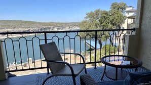 A balcony with a view of a body of water, a chair, and a small round table. - Amazing top floor view in a newly renovated Lake Travis Condo on Private Island (Lago Vista)