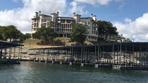 A multi-story building with balconies, located near a body of water with a dock. - Amazing top floor view in a newly renovated Lake Travis Condo on Private Island (Lago Vista)
