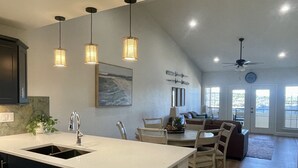 A spacious kitchen with a large island, pendant lights, and a dining area with a view of the outdoors. - Amazing top floor view in a newly renovated Lake Travis Condo on Private Island (Lago Vista)