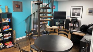 A living room with a spiral staircase, a round table, a sofa, and a bookshelf. - Clemson Football- Lake Hartwell Lakefront Cabin Private Dock 4 BR (Fair Play)