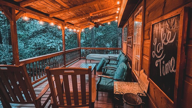 A wooden porch with string lights, a sofa, and a sign that reads "Lake Time". - Clemson Football- Lake Hartwell Lakefront Cabin Private Dock 4 BR (Fair Play)