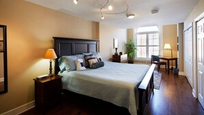 A bedroom with a large bed, bedside tables, a desk, and a chair.