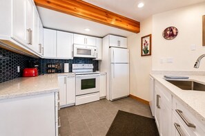 A modern kitchen with white cabinetry, a microwave, oven, and refrigerator. - True Ski In / Out with Amazing Views, Garage, Elevator & Fireplace (Crested Butte)