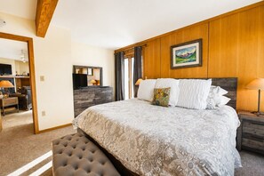 A bedroom with a large bed, a wooden headboard, a painting, and a desk with a chair. - True Ski In / Out with Amazing Views, Garage, Elevator & Fireplace (Crested Butte)