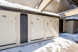 A row of numbered lockers, 102 to 104, against a building facade with a snow-covered roof.